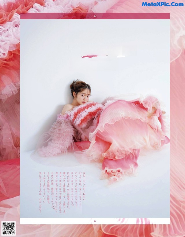 A woman in a pink dress laying on a bed of pink tulle.