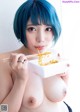 A woman with blue hair eating noodles with chopsticks.