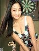 A woman in a bathing suit posing in front of a dart board.