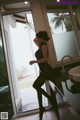 A woman in a black dress standing in front of a window.