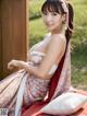 A woman in a kimono sitting on a bed.