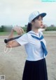 A woman in a sailor outfit holding a baseball bat.