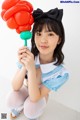 A woman in a blue and white outfit holding a red balloon.