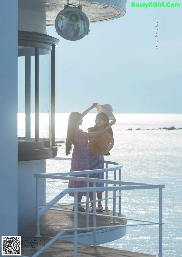 A couple of women standing on top of a pier next to the ocean.