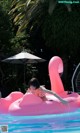 A woman in a bikini laying on an inflatable flamingo in a pool.