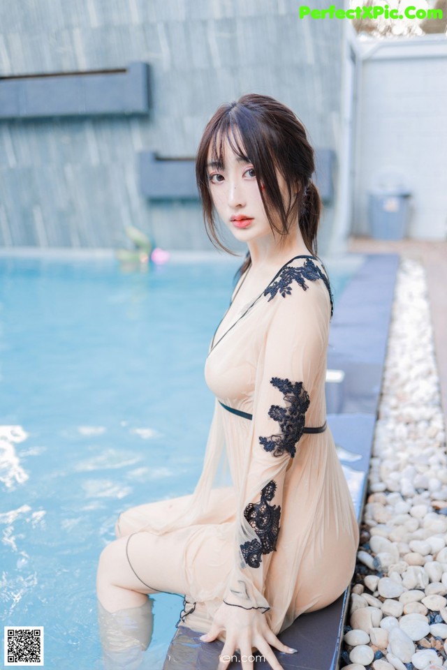 A woman sitting on the edge of a swimming pool.