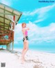 A woman in a pink bikini standing on a beach.