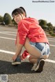 A woman crouching down on the side of a road.